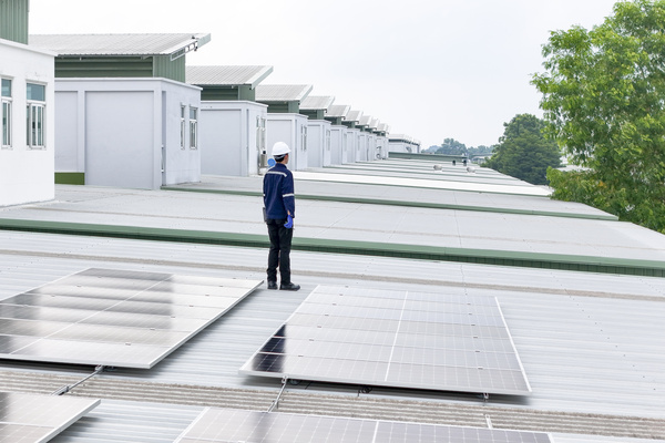 technician in hard hat and safety gear inspects solar panels on